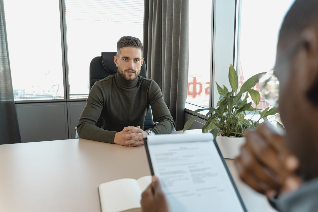 Professional man in turtleneck at office desk during an interview.