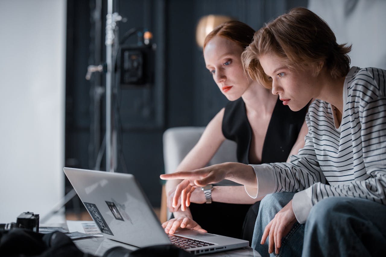 Two focused individuals collaborating on a laptop in a professional indoor setting.